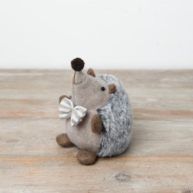 A cute hedgehog plush adorned with a neutral striped bow and a fluffy grey back.