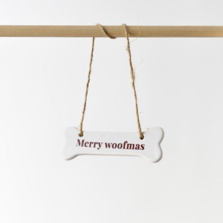 An adorable ceramic ornament featuring the words "Merry Woofmas" in a deep red text.