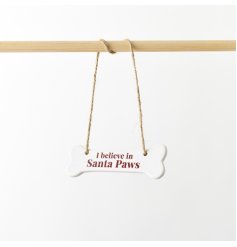 A charming ceramic hanger shaped like a bone, featuring the phrase "I Believe in Santa Paws."