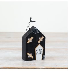 A stylish wooden house with Halloween features including a bat and boarded up windows. 