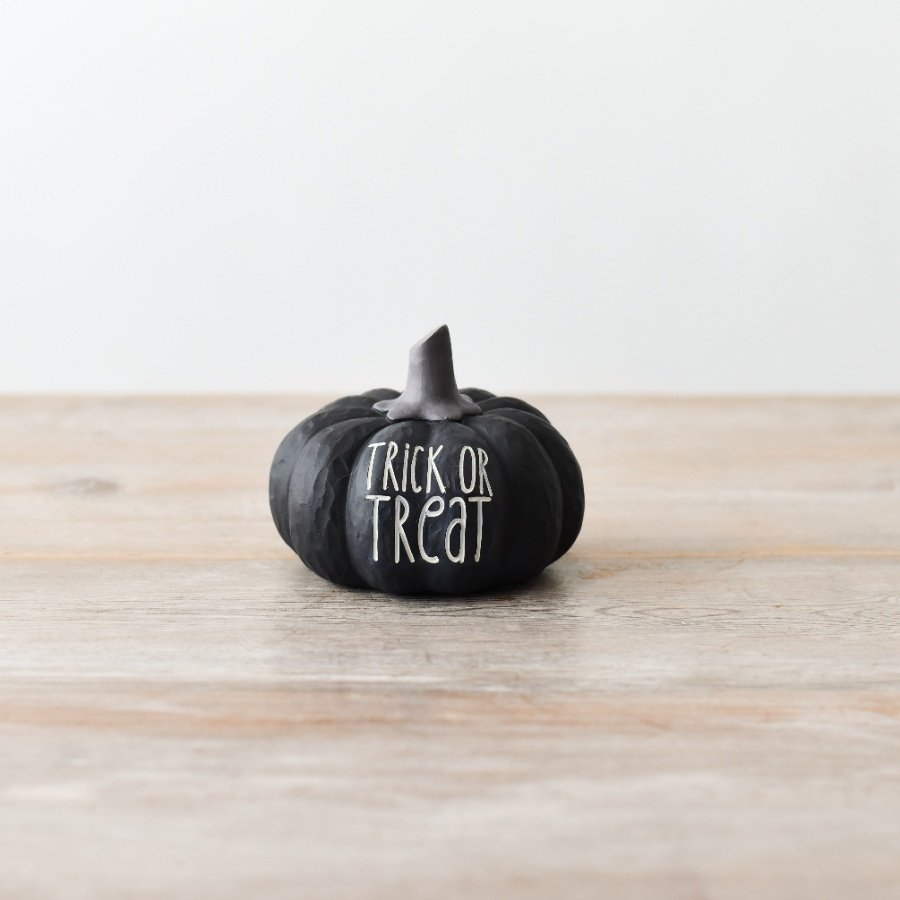 A haunting black pumpkin decoration with the words 'Trick or Treat' in white text.