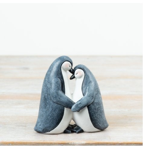 A beautifully styled ornament featuring two penguins standing close in an affectionate embrace.