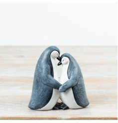 A charming penguin couple ornament featuring two gently embracing penguins with a soft grey and white finish