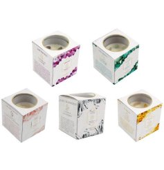 An assortment of 5 wellbeing candles containing crystals boxed in coloured packaging.