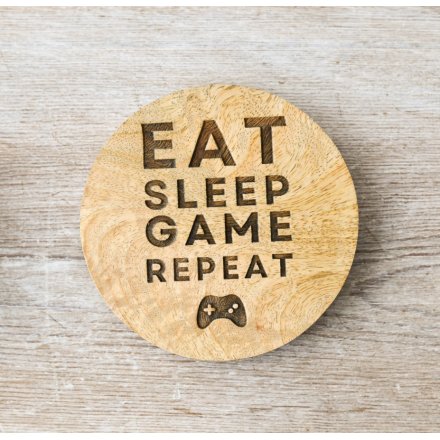 A wooden coaster with a simple finish, featuring a quirky gaming slogan and console decal. 