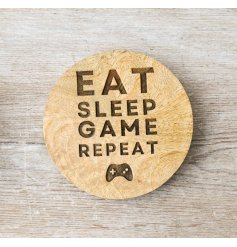 A wooden coaster with a simple finish, featuring a quirky gaming slogan and console decal. 
