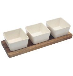 This set includes three ceramic dishes in a speckled white, beautifully complemented by a natural tone wooden tray.