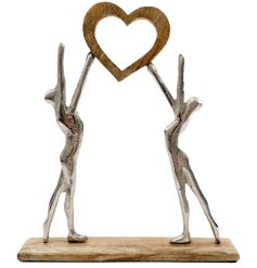 Set on a chunky wooden base, a couples figurine holding a wood heart. 