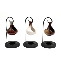 A lovely glazed oil burner hung from a black arched stand in 3 assorted designs. 