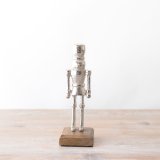 A chic and elegant silver nutcracker decoration with a rustic wooden base. 