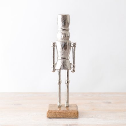 An elegant nutcracker decoration with a rustic wooden base. 