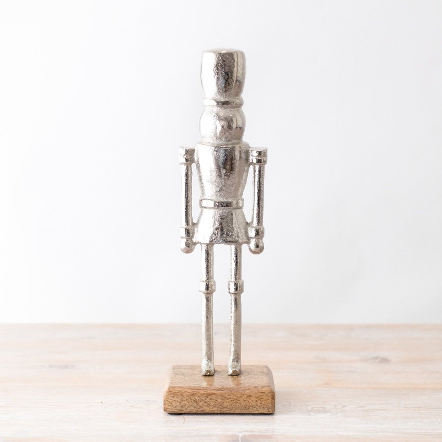 A chic and stylish silver nutcracker ornament with a rustic wooden base.