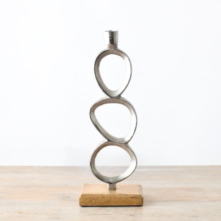 A simplistic candle stand in chrome set on a chunky wooden base.