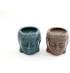 A chic detailed boho style candle featuring a buddha head design and scented wax. 
