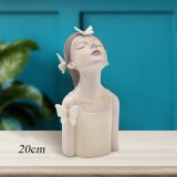 Girl head figurine ideal to placed on a desk, shelf, or mantle, its elegant presence enhances the ambiance of any room.