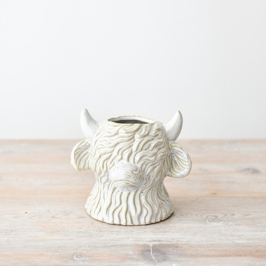 Cow-shaped planter made of white ceramic, featuring a charming highland cow design.