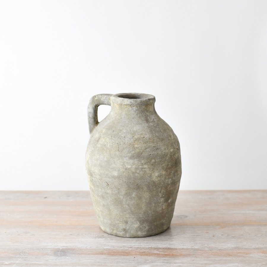 A rustic terracotta jug in a neutral hue with a beautifully textured surface.