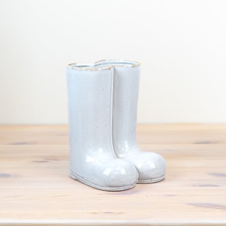 A tall porcelain vase in the design of a pair of boots.
