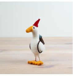 An adorable felt goose with a festive red hat and backpack with a little Christmas tree inside. 