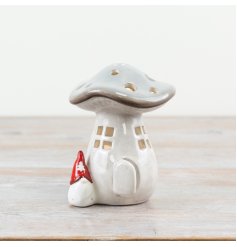 A grey ceramic mushroom candle house with cut out windows and doors.