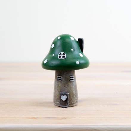 A whimsical green mushroom house complete with painted windows and a 3d door and heart. 