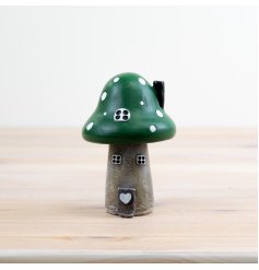 A whimsical green mushroom house complete with painted windows and a 3d door and heart. 