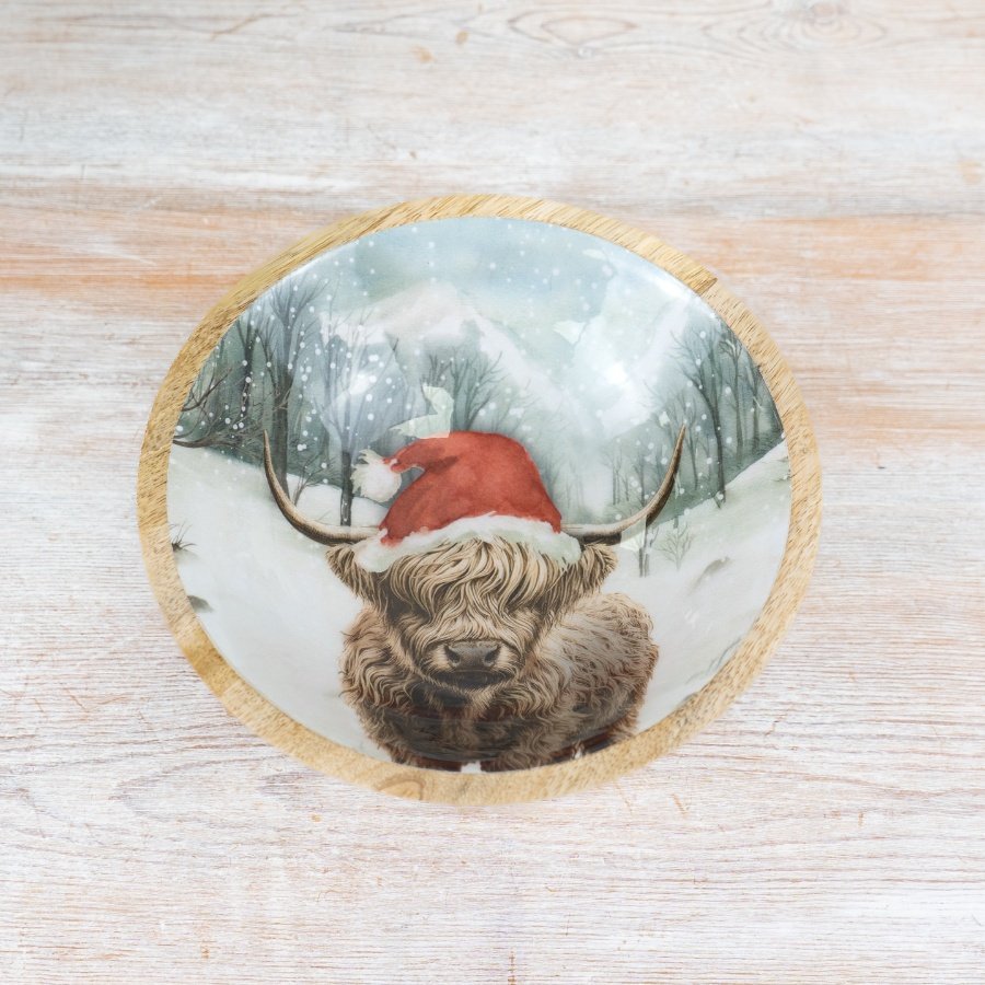 A rustic artisan bowl made from natural mango wood. Inside a beautiful snow scene is depicted with a highland cow. 