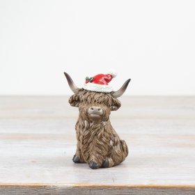 Add a touch of holiday cheer to the home with this charming highland cow figurine.