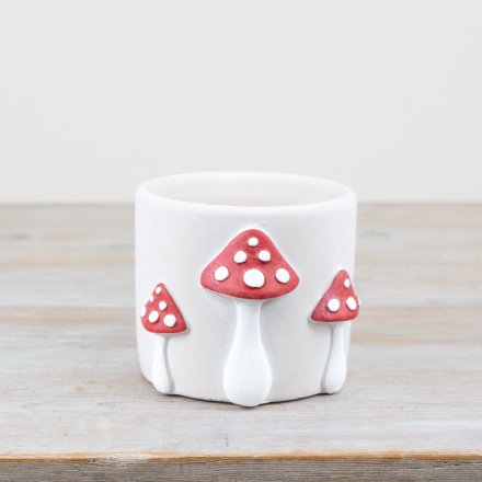 A whimsical cement planter featuring 3D red mushrooms with white spots.