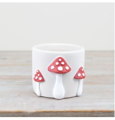 A whimsical cement planter featuring 3D red mushrooms with white spots.