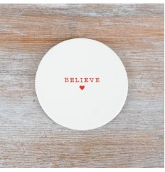 A simple ceramic coaster with the phrase "Believe" embossed in red and complete with a little heart.