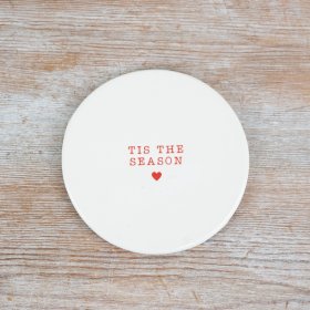 A charming ceramic coaster, featuring the phrase "Tis the Season" embossed in a vibrant red font 