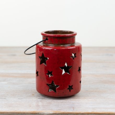 A rustic red glazed lantern with star cut outs.