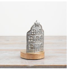 An aluminium house with a wooden base and a candle holder