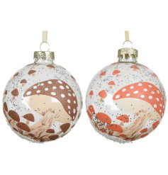 An assortment of 2 transparent glass baubles with a glitter mushroom decal in burnt orange and brown designs. 