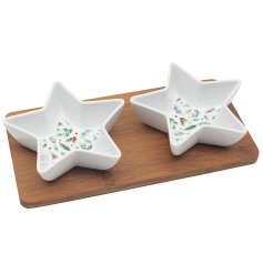A stylish bamboo tray with 2 star shaped dishes, each featuring a red berry and winter foliage design. 