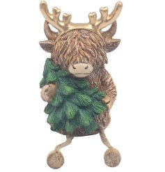 A beautifully crafted highland cow shelf sitter, complete with gold antlers and a Christmas tree. 
