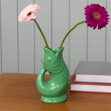 A stylish vase in the shape of a fish in a striking green colour. 