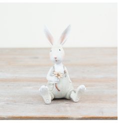 Adorable white bunny wearing dungarees, carrying a flower.