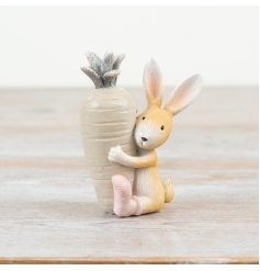 Adorable white and brown bunny figurine clutching a vivid orange carrot.