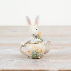 A whimsical teapot decoration with a white bunny and tulips. 