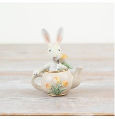 A charming teapot decoration featuring a white rabbit and flowers. 