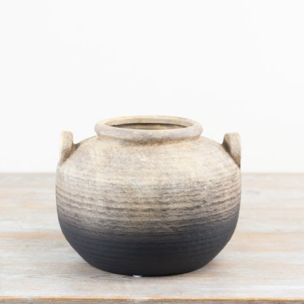 An artisan terracotta pot with a rustic surface and imperfect details, which enhance the character and charm of the item