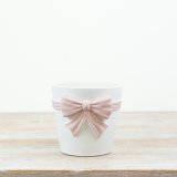 A simple yet elegant planter in white with an oversized bow in a pastel pink displayed around the front. 