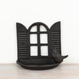 A rustic bird feeder made from cast iron featuring a lovely open window scene.