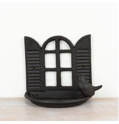 A rustic bird feeder made from cast iron featuring a lovely open window scene.