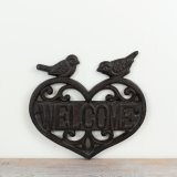 A rustic welcome sign made from cast iron featuring a heart shape design.