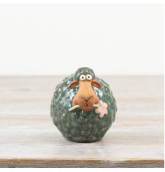 Delightful green sheep figurine made of porcelain, holding a delicate flower.