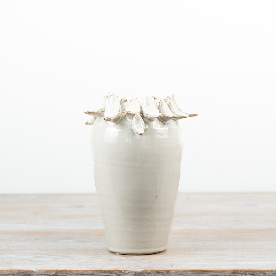 Delightful bird perched on rim of a natural-toned vase.