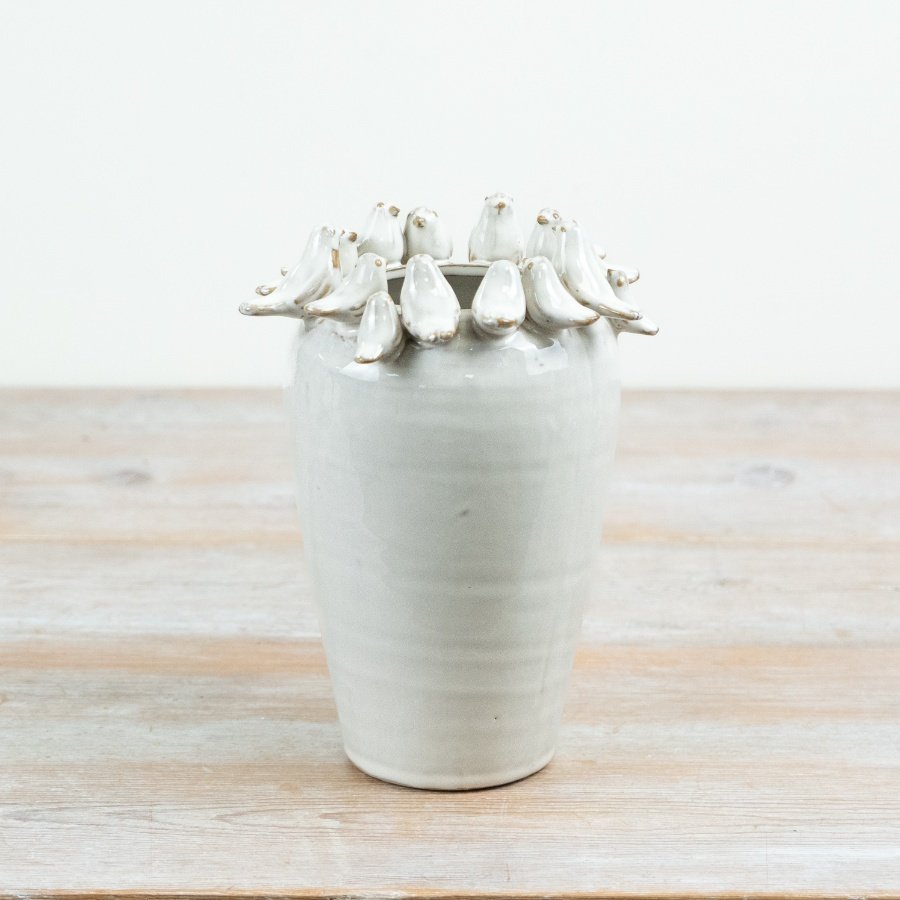 Delightful bird perched on rim of a natural-toned vase.